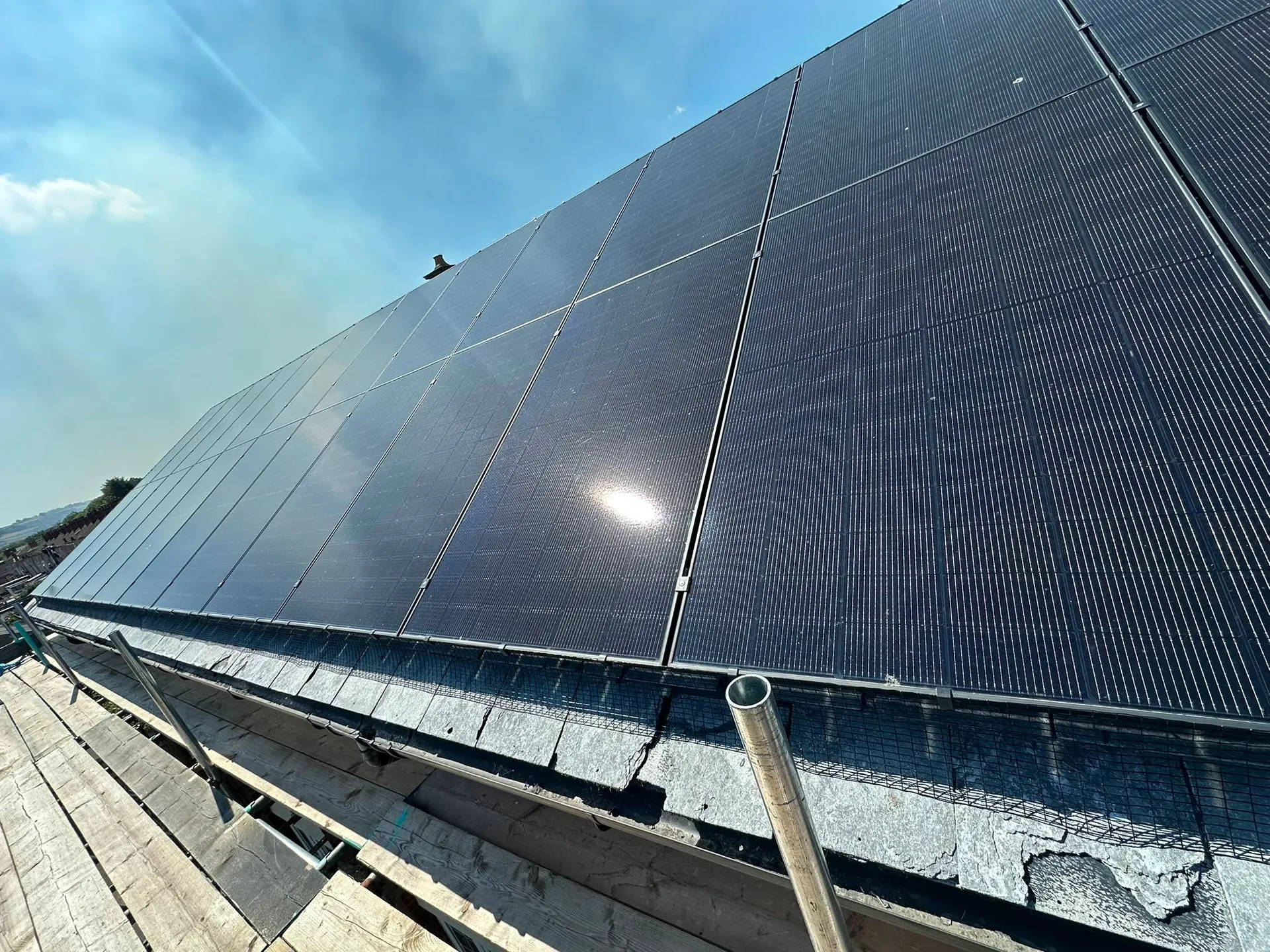 Dark solar panels covering a pitched roof in bright sunlight