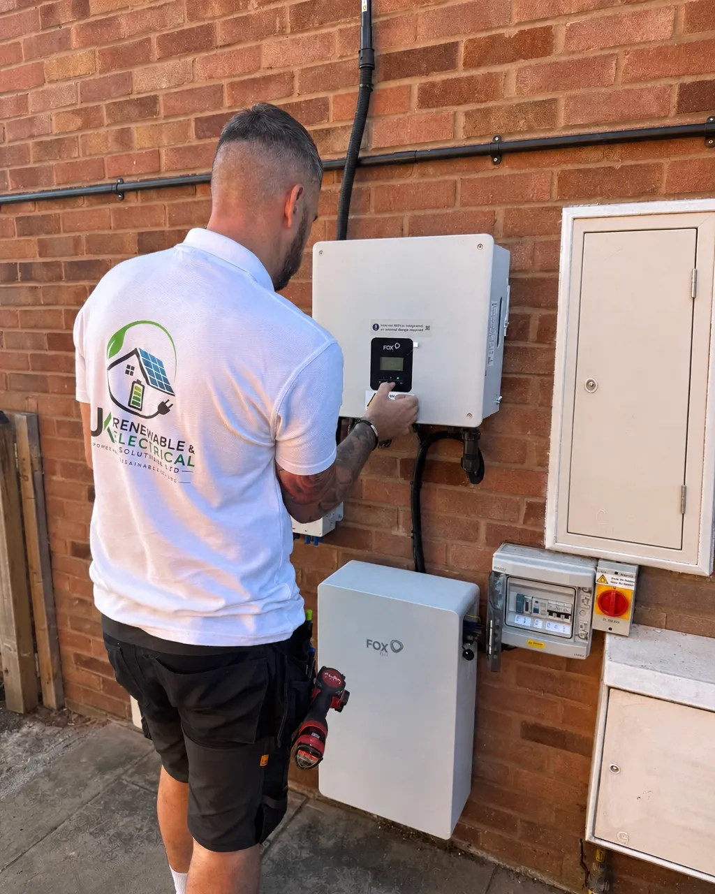 Electrician checking a Fox battery system beside a completed meter cupboard installation